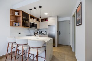 A modern kitchen with a central island, bar stools, built-in shelves, and a microwave. - w Scenic 1BR w Balcony View in San Francisco (Panama City)