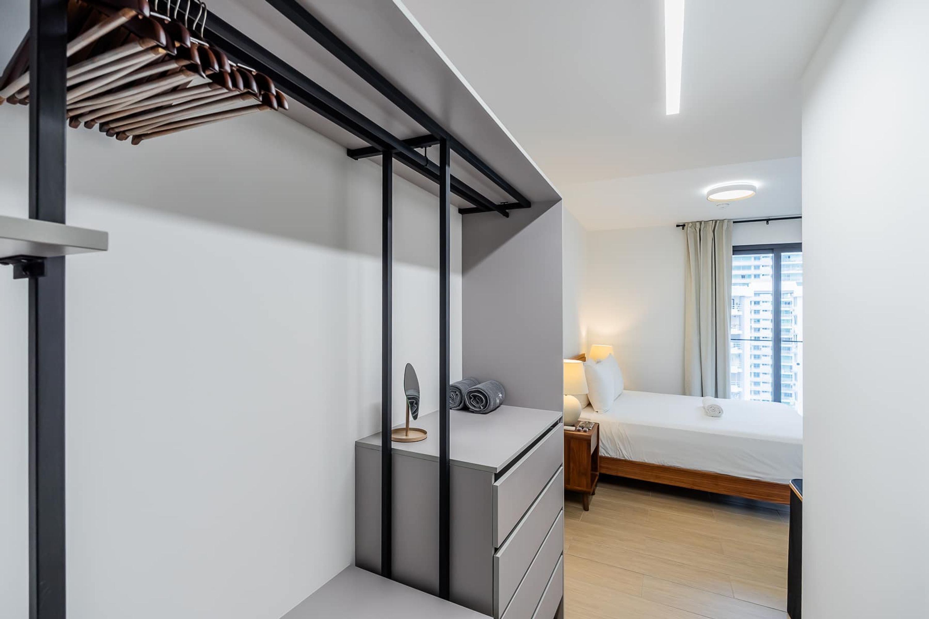 Une chambre d’hôtel moderne équipée d’un lit, d’une table de chevet et d’un bureau intégré avec des tiroirs.