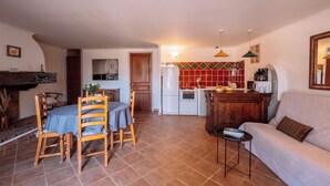 A living room with a sofa, a dining table with chairs, a kitchen area with a refrigerator, stove, and microwave.
