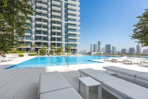 Ein Pool auf dem Dach mit Liegestühlen und Blick auf ein Hochhaus.