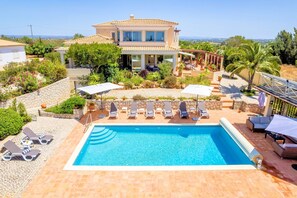 A two-story house with a swimming pool, sun loungers, and a view of the landscape. - Casa Serrao | Carvoeiro | Private Pool & Sea Glimpses | Walk to Dining & Beaches (Carvoeiro)
