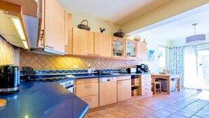 Uma cozinha com armários de madeira, bancada azul e piso ladrilhado.
