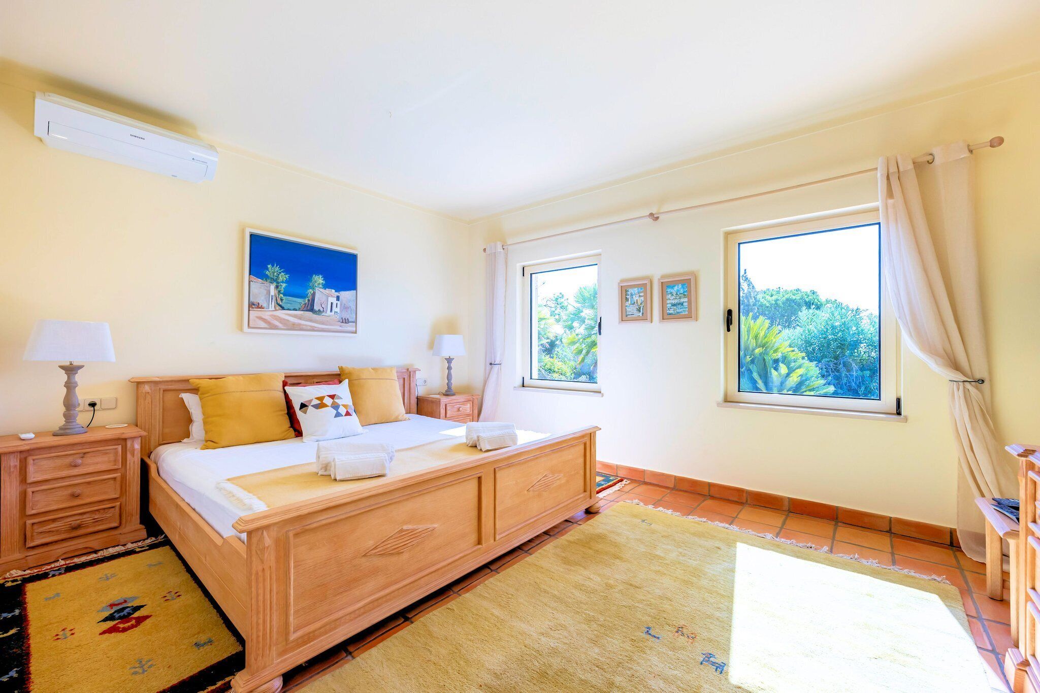 Una camera da letto con un letto di legno, due comodini, una finestra con tende e un quadro appeso al muro.