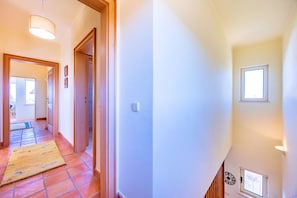 A hallway with a tiled floor, a wooden door, a light fixture, and a small window. - Casa Serrao | Carvoeiro | Private Pool & Sea Glimpses | Walk to Dining & Beaches (Carvoeiro)