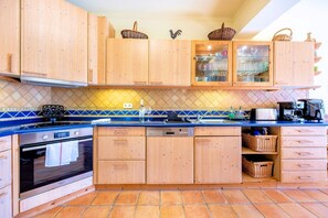 A kitchen with wooden cabinets, a blue countertop, a stainless steel oven, and a tiled backsplash. - Casa Serrao | Carvoeiro | Private Pool & Sea Glimpses | Walk to Dining & Beaches (Carvoeiro)