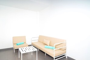 A minimalist room with a white metal bed frame, a beige sofa, and a white table. - Villa Maravento | Playa Blanca | Heated Pool | Family Luxury Retreat (Playa Blanca)