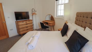 Habitación de hotel con cama, televisor, escritorio y ventana.