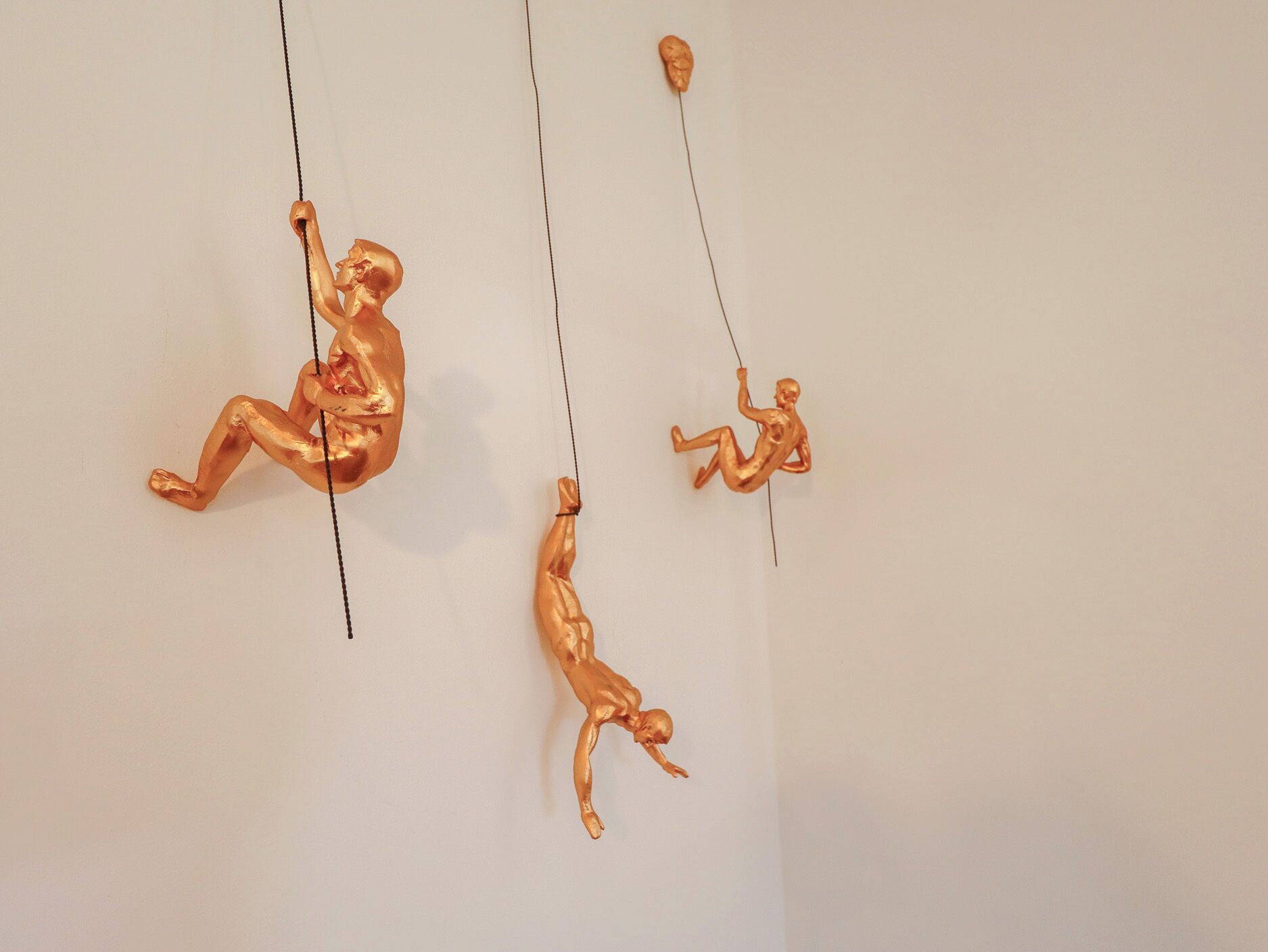 Three golden sculptures suspended from the ceiling.