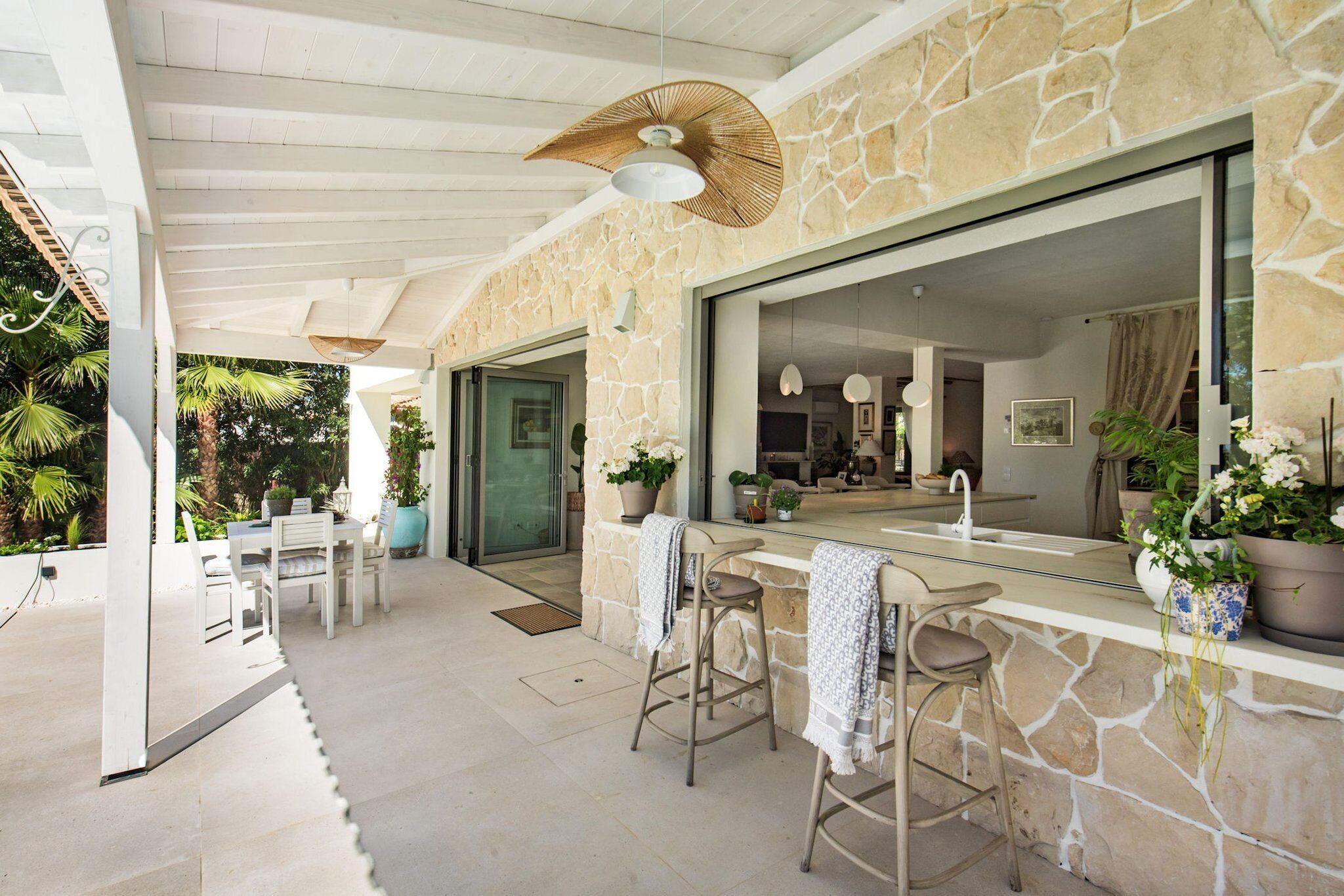 A modern kitchen with a stone facade, a large window, and a bar area with stools.