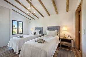 A hotel room with two beds, wooden beams on the ceiling, a window with a view, and bedside lamps. - Villa Azurea | Almancil Algarve | 4BR Retreat | Private Pool & Terrace (Almancil)