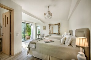 Ein Schlafzimmer mit zwei Betten, einer Chandelier, einem Spiegel und einer Tür, die auf einen Balkon führt.