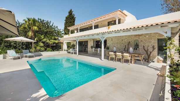 Ein zweistöckiges Haus mit Swimmingpool, Sitzgelegenheiten im Freien und einer überdachten Terrasse.