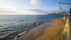 Una playa con cielo despejado, mar tranquilo y orilla arenosa.