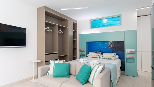 Un dormitorio moderno con cama, sofá, armario y televisor.