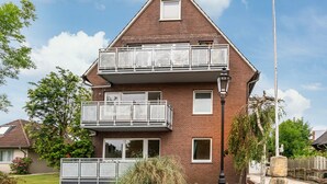 Un bâtiment de deux étages en briques, doté d’un balcon à l’étage supérieur, d’une petite fenêtre au deuxième étage et d’un lampadaire devant.
