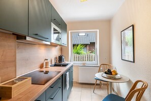 Eine kleine Küche mit Fenster, einem Esstisch mit Stühlen und einer Heizung.