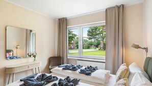 Ett hotellrum med två sängar, en sittgrupp, ett fönster med utsikt och en spegel på väggen.