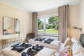 Ein Hotelzimmer mit zwei Betten, einer Sitzecke, einem Fenster mit Außenblick und einem Spiegel an der Wand.