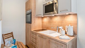 Eine kleine Küche mit Mikrowelle, Backofen, Spüle und Holzschränken.