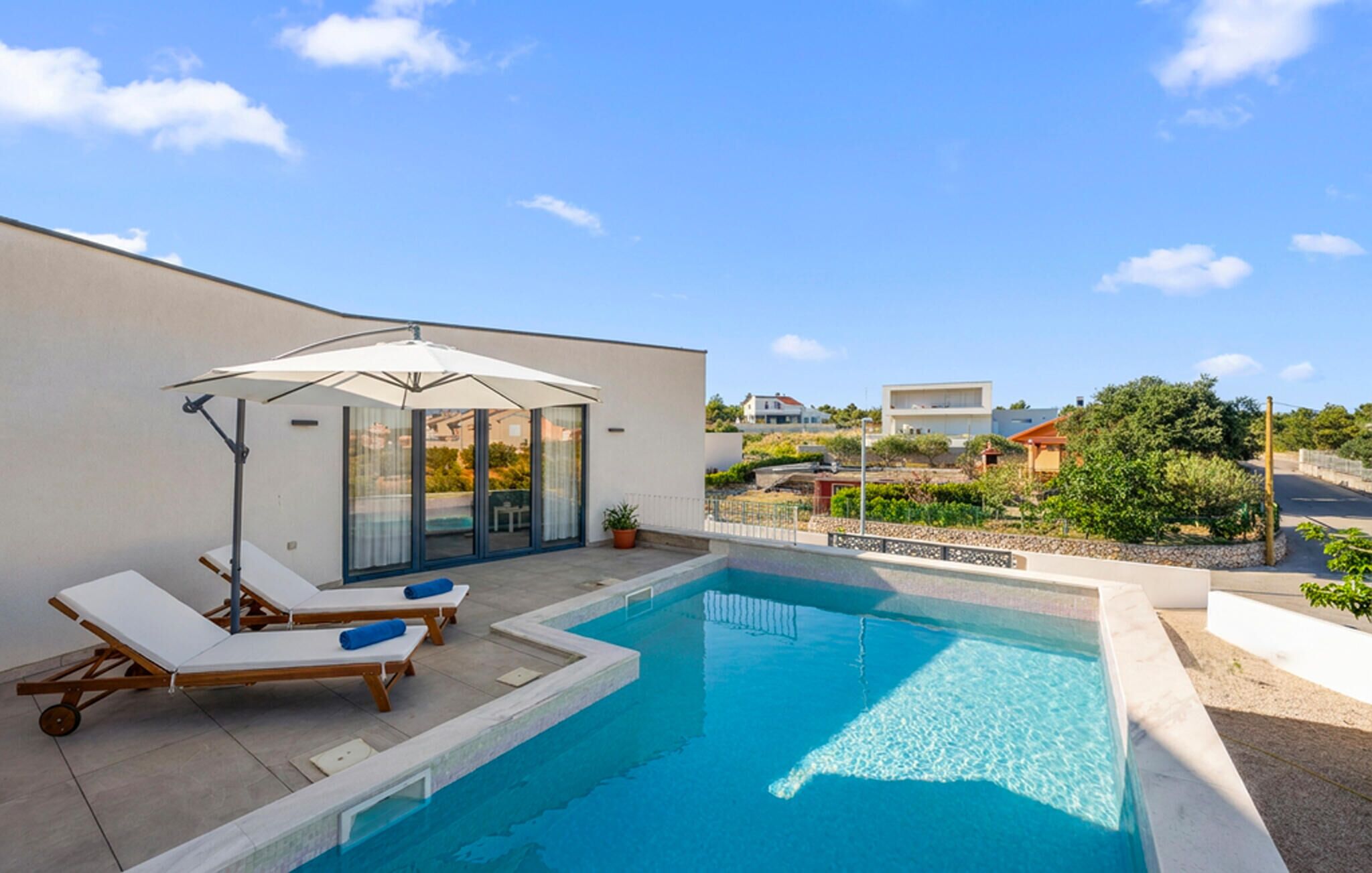 A modern outdoor pool area with lounge chairs and a covered seating area.