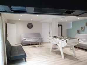 A modern living room with a foosball table, a sofa, and a coffee table. - Gîte Maisolys (Le Bouchet-Saint-Nicolas)