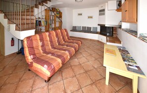 Ein Wohnzimmer mit einem gestreiften Sofa, einer Holztreppe, einem Bücherregal und einem kleinen Tisch mit Zeitschriften.