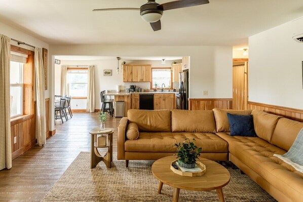 A living room with a sofa, a coffee table, and a dining area with chairs.
