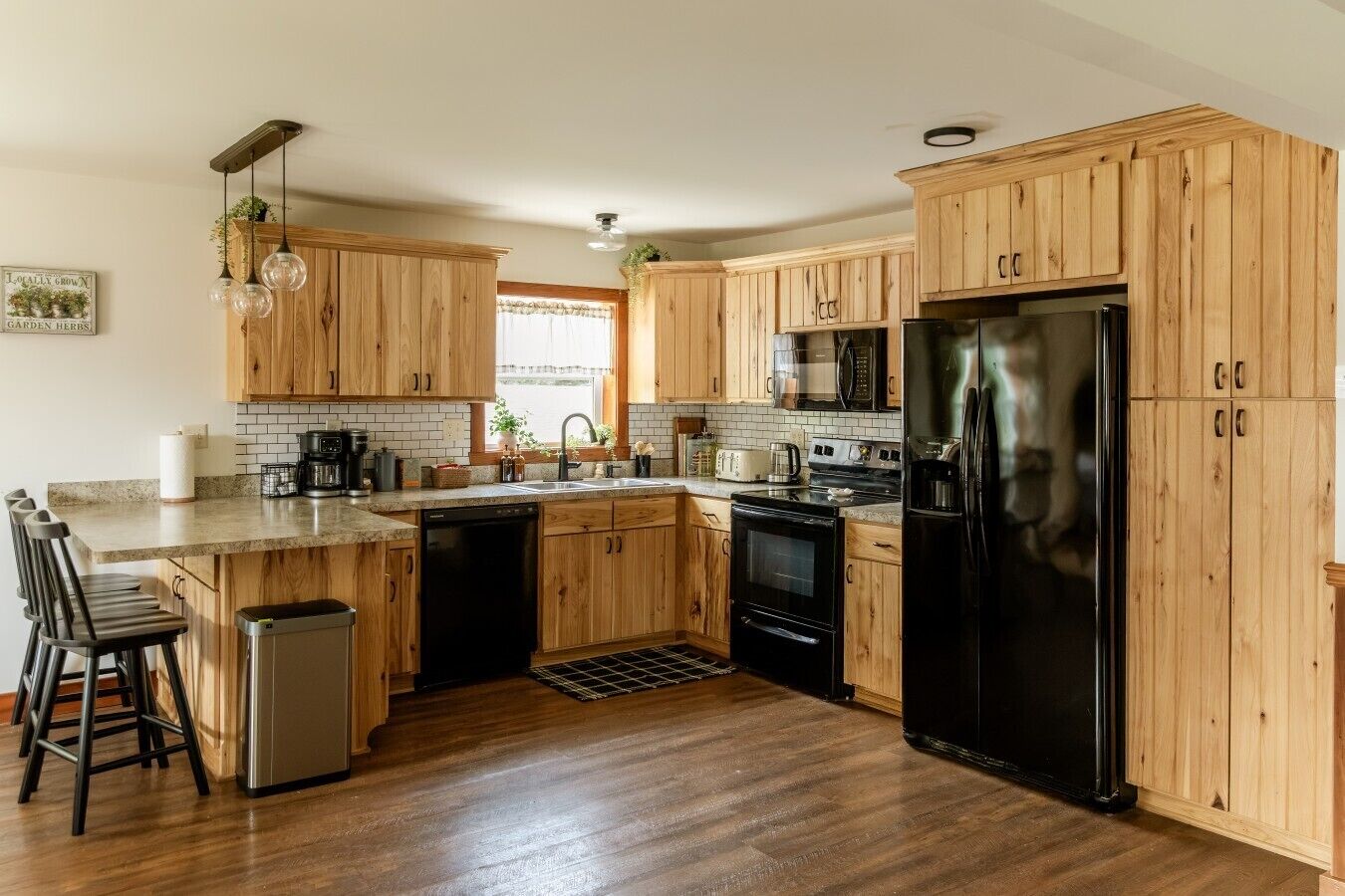 A kitchen with wooden cabinets, a black refrigerator, a microwave, and a dishwasher.