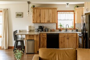 A kitchen with wooden cabinets, a coffee maker, and a dishwasher. - Valley View Retreat| Close to Downtown| Sleeps 7 (Shippensburg)