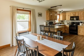Una cocina moderna con armarios de madera, una isla central y un comedor con mesa y sillas.