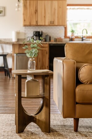 A brown leather armchair and a wooden side table with a vase of green leaves.