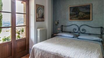 A bedroom with a bed, a radiator, a window, and a painting on the wall.