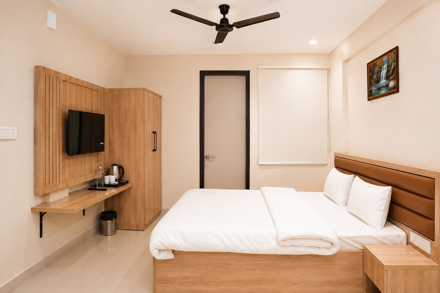 Quarto com uma cama, televisão, ventoinha no teto, um quadro e uma porta.