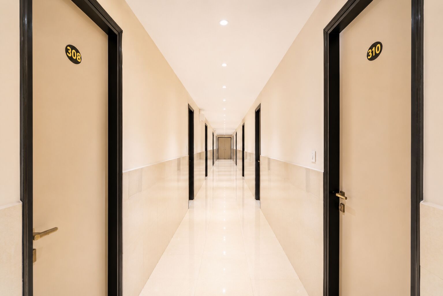 A long, well-lit hallway with doors numbered 308 and 310, leading to rooms.