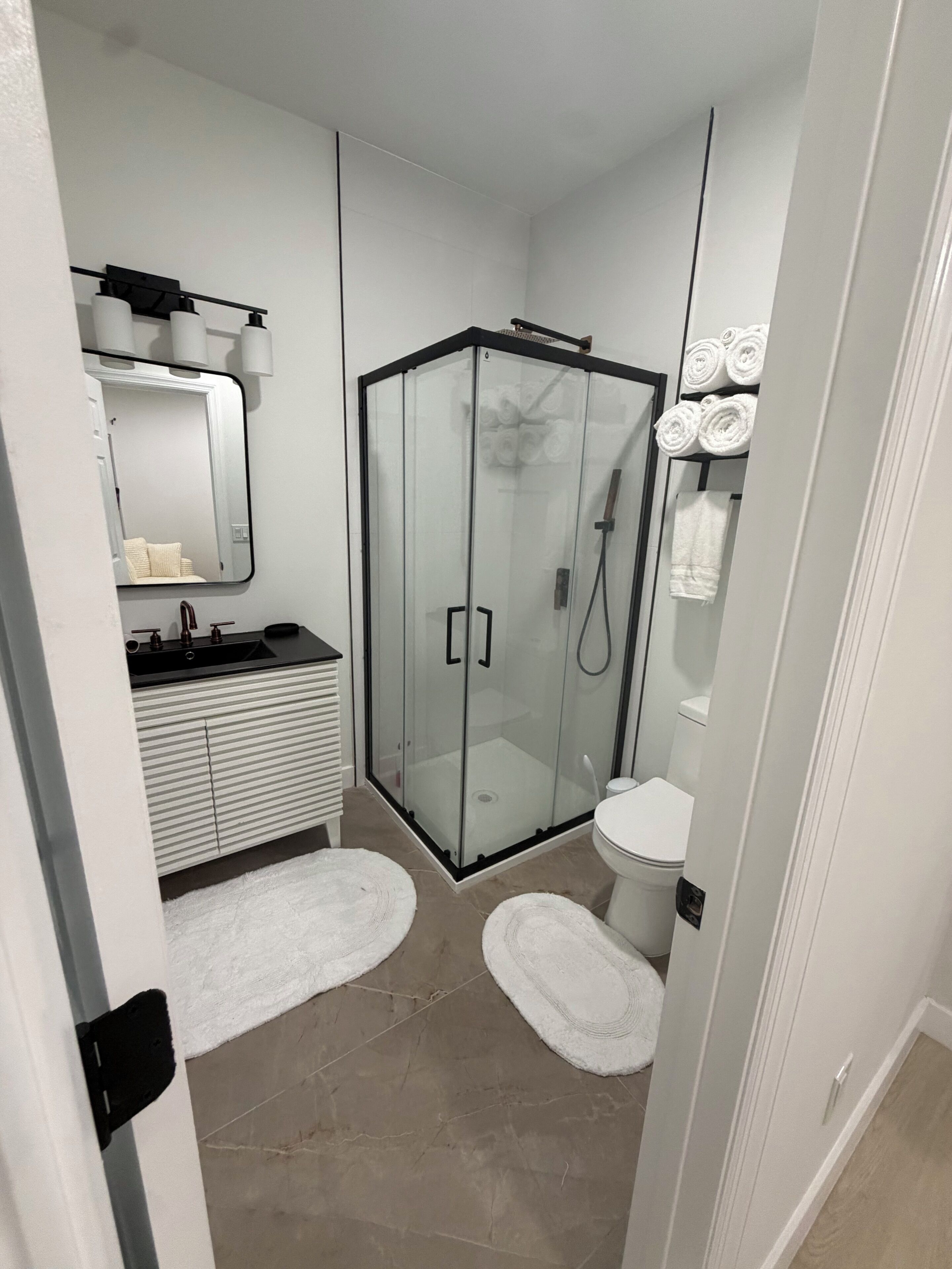 A compact bathroom with a glass-enclosed shower, a white sink, and a toilet.