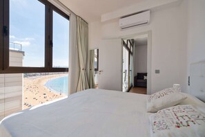 Ein Hotelzimmer mit einem großen Bett, Blick auf einen Strand und einer Klimaanlage.