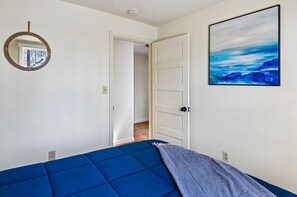 Ein Schlafzimmer mit Bett, einer Tür, einem Wandspiegel und einem Gemälde.