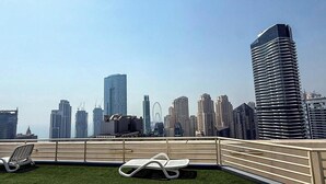 Um terraço no telhado com vista para o horizonte urbano, incluindo edifícios altos e uma roda gigante.