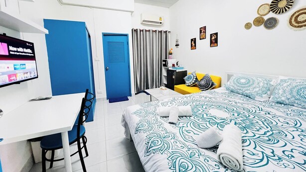 A hotel room with a bed, a desk, a chair, a television, and a bathroom door. - Room-105 Budget Room, Wifi&utilities Ban (Bangkok)