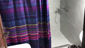 Een badkamer met een douche, toilet en een roze vloerkleed.