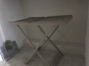 Ein Metalltisch mit einer Metallplatte und einem einfachen Kreuzgestell, an einer schlichten Wand platziert.
