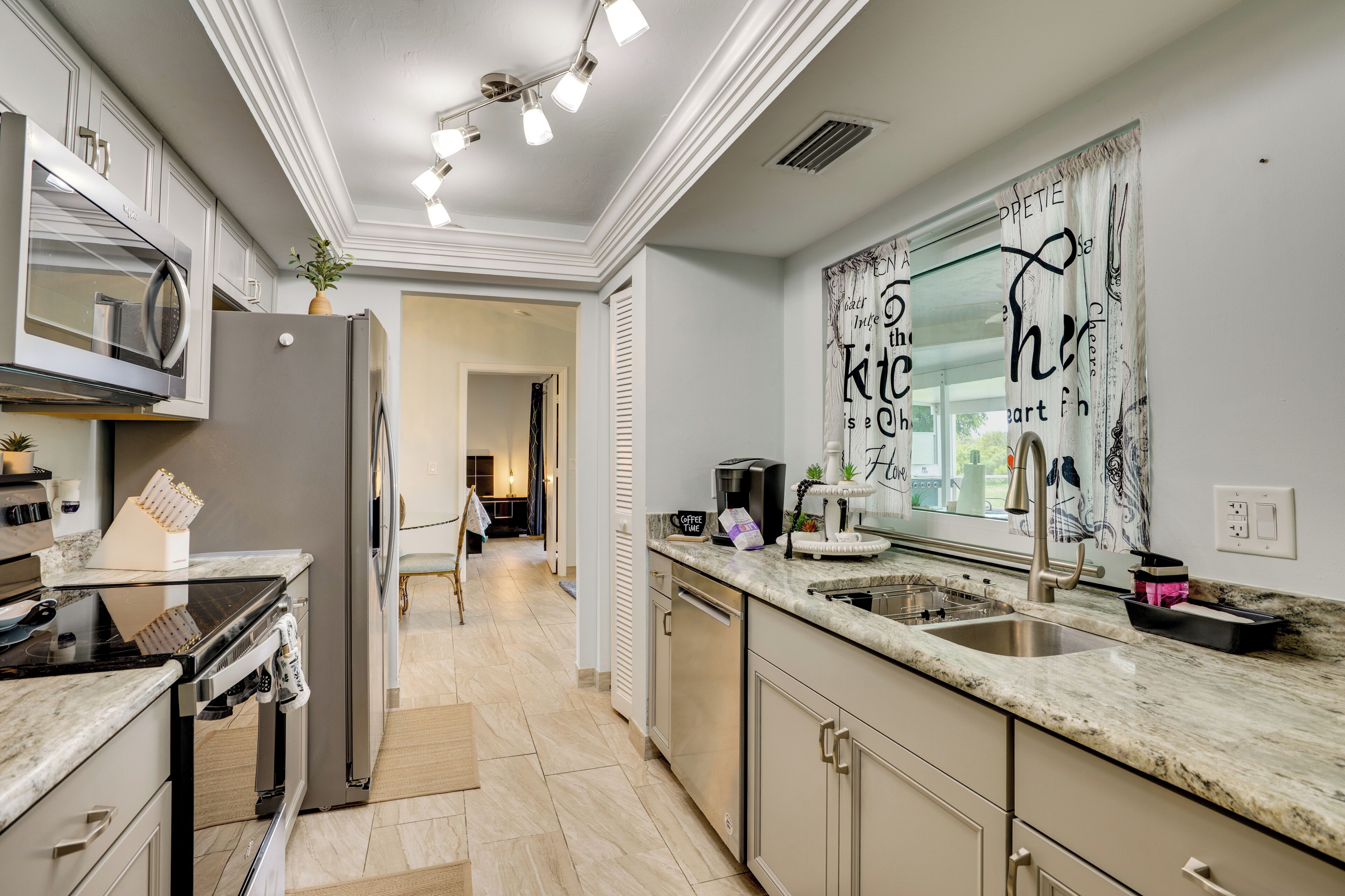 A modern kitchen with a central island, stainless steel appliances, and a decorative wall piece.