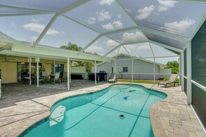 A covered outdoor swimming pool with a patio area, chairs, and a view of the surrounding landscape. - On Preserved Land w/ Pool & Trails! Cape Coral Gem (Cape Coral)