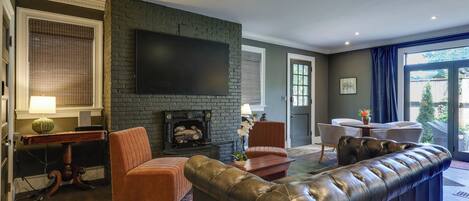 A living room with a fireplace, leather sofa, and a flat-screen TV.