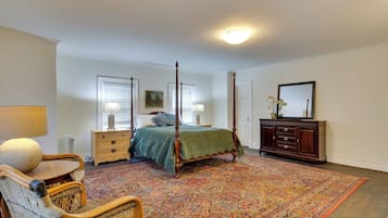 A bedroom with a four-poster bed, a dresser, a chair, and a large rug.