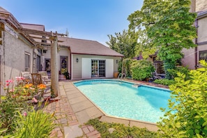 Ein Garten mit Swimmingpool, einer Pergola und einer Terrassenanlage mit Gartenmöbeln.