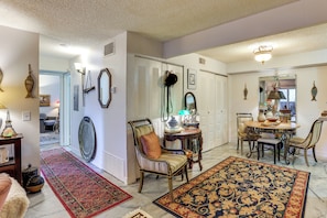 A spacious living area with a dining table, chairs, a patterned rug, and a chair with a cushion. - Walk to Parks & Dining! Lakewood Condo w/ Balcony (Lakewood)