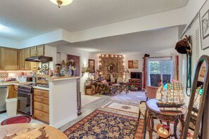 A spacious living area with a fireplace, a dining table, and a kitchen area with wooden cabinets and appliances. - Walk to Parks & Dining! Lakewood Condo w/ Balcony (Lakewood)