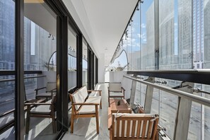 Ein Balkon mit Sitzgelegenheit, großen Fenstern und Blick auf die Stadt.