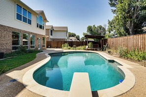 Ein Garten mit Swimmingpool, Holzterrasse und umzäunter Fläche.